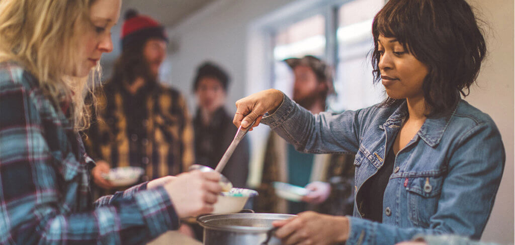 Woman serving a homeless person soup